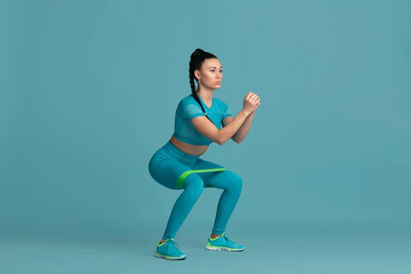 Bella giovane atleta femminile che pratica su sfondo blu studio, ritratto monocromatico — Foto Stock