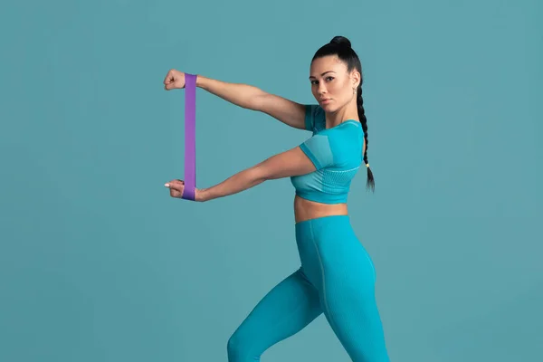 Krásná mladá žena sportovec cvičení na modrém pozadí studia, monochromatický portrét — Stock fotografie