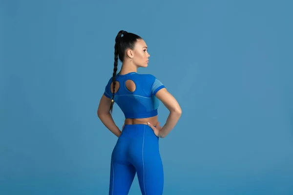 Linda jovem atleta praticando no fundo do estúdio azul, retrato monocromático — Fotografia de Stock