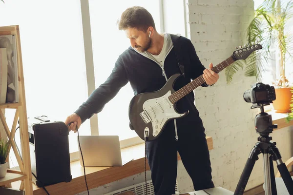 Musicien caucasien jouant de la guitare lors d'un concert en ligne à la maison isolé et mis en quarantaine, accordant le flux — Photo