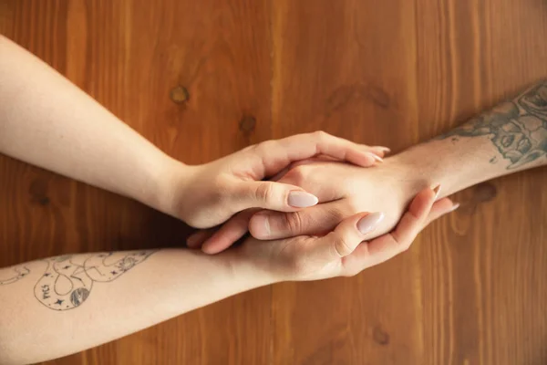 Loving couple holding hands close-up on wooden background, romantic — Stock Photo, Image