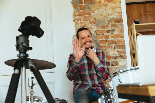 Músico caucasiano tocando bateria durante concerto online com a banda em casa isolado e em quarentena, cumprimentando o público — Fotografia de Stock