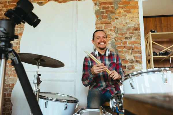 Caucasian musician playing drumms during online concert with the band at home isolated and quarantined, greeting audience