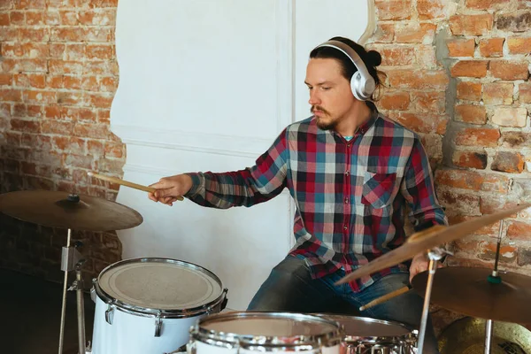 Caucasian musician playing drumms during online concert with the band at home isolated and quarantined, inspired improvising