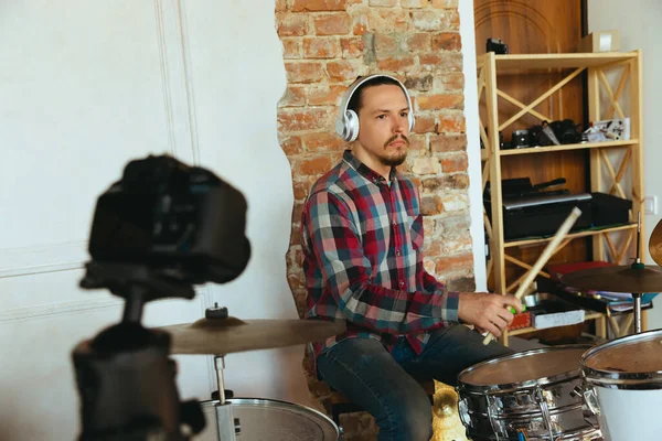 Caucasian musician playing drumms during online concert with the band at home isolated and quarantined, inspired improvising