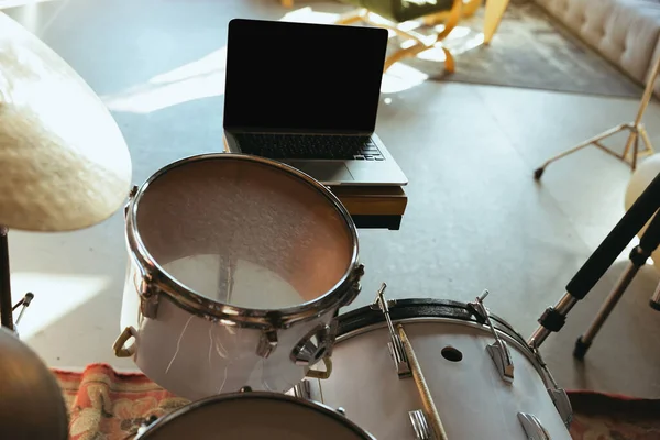 Músico caucasiano tocando bateria durante concerto online com a banda em casa isolado e em quarentena, foco na tela do laptop em branco — Fotografia de Stock