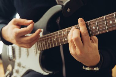 Evde konser sırasında gitar çalan beyaz müzisyen tecrit edilmiş ve karantinaya alınmış, neşeli doğaçlama, yakın çekim.