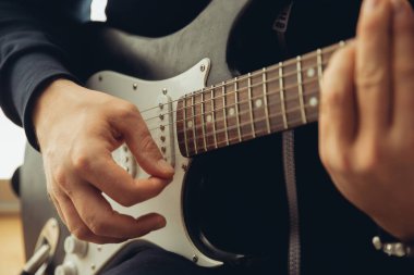 Evde konser sırasında gitar çalan beyaz müzisyen tecrit edilmiş ve karantinaya alınmış, neşeli doğaçlama, yakın çekim.