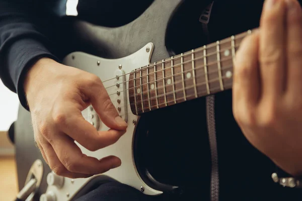 Músico caucasiano tocando guitarra durante concerto em casa isolado e em quarentena, alegre improvisação, close-up — Fotografia de Stock