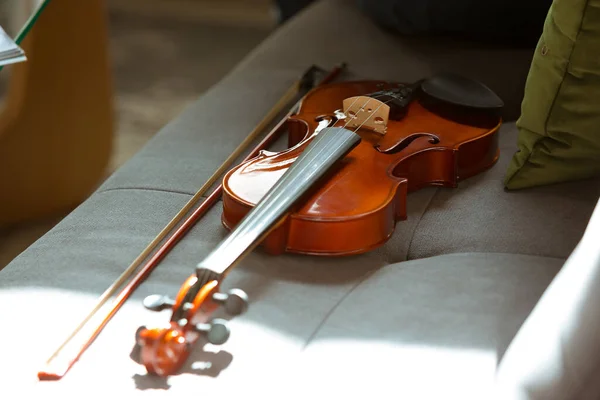 Gros plan prise de vue de violon couché sur le canapé dans la lumière du soleil, passe-temps et concept de musique — Photo