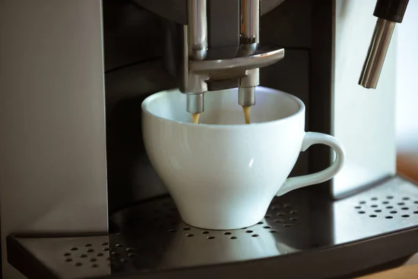 Großaufnahme einer Kaffeemaschine, die Cappuccino, Espresso, American in weißer Tasse einschenkt — Stockfoto