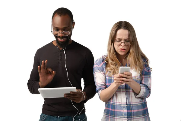 Эмоциональные мужчина и женщина, используя гаджеты на белом фоне студии, технологии, соединяющие людей. Игры, шоппинг, онлайн встречи — стоковое фото