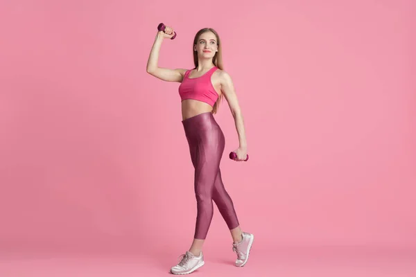 Linda jovem atleta praticando no fundo do estúdio rosa, retrato monocromático — Fotografia de Stock