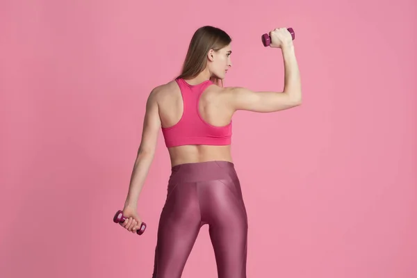 Linda jovem atleta praticando no fundo do estúdio rosa, retrato monocromático — Fotografia de Stock