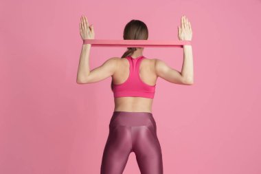 Pembe stüdyo arka planında pratik yapan güzel genç bayan sporcu, tek renkli portre.