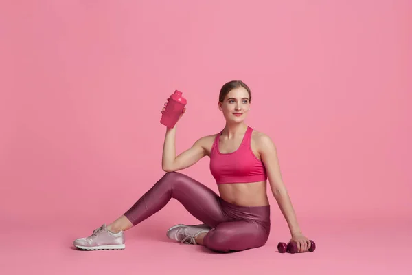 Krásná mladá žena sportovec cvičení na růžové pozadí studia, monochromatický portrét — Stock fotografie