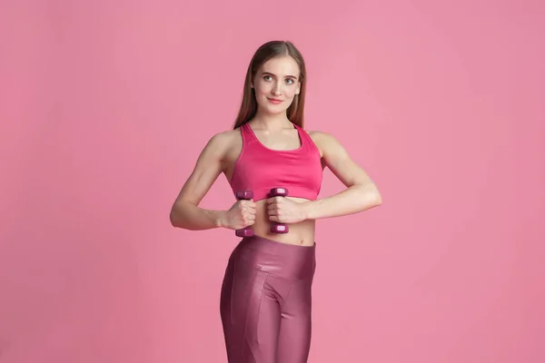 Vacker ung kvinnlig idrottare tränar på rosa studio bakgrund, monokrom porträtt — Stockfoto