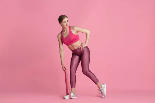 Hermosa joven atleta practicando sobre fondo de estudio rosa, retrato monocromo — Foto de Stock