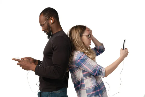 Emocjonalny mężczyzna i kobieta wykorzystujący gadżety na białym tle studia, technologie łączące ludzi. Gry, zakupy, spotkanie online — Zdjęcie stockowe