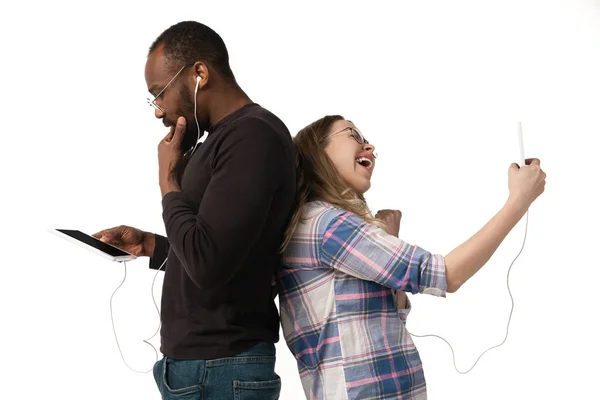 Emocionální muž a žena pomocí gadgets na bílém pozadí studia, technologie spojující lidi. Gaming, nakupování, online setkání — Stock fotografie