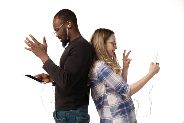 Emocjonalny mężczyzna i kobieta wykorzystujący gadżety na białym tle studia, technologie łączące ludzi. Gry, zakupy, spotkanie online — Zdjęcie stockowe