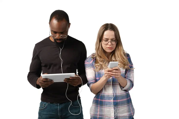 Homme et femme émotionnels utilisant des gadgets sur fond de studio blanc, technologies connectant les gens. Jeux, shopping, réunion en ligne — Photo