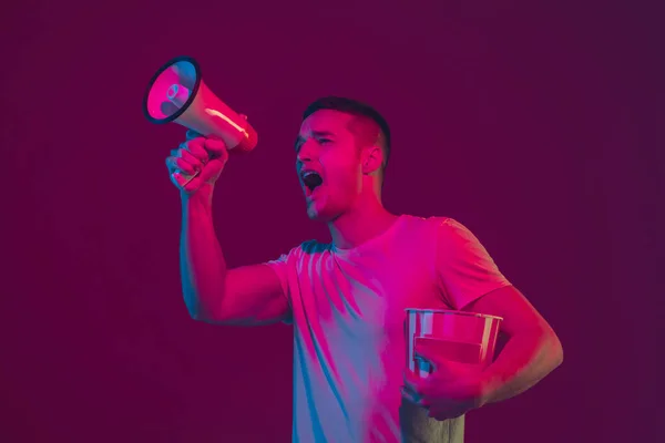 Caucasian mans portrait isolated on pink-purple studio background in neon light, using speaker — Stock Photo, Image