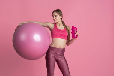 Pembe stüdyo arka planında pratik yapan güzel genç bayan sporcu, tek renkli portre.