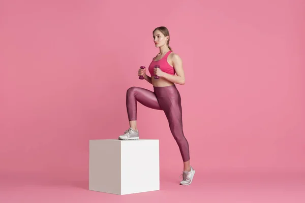 Gyönyörű fiatal női sportoló gyakorló rózsaszín stúdió háttér, monokróm portré — Stock Fotó