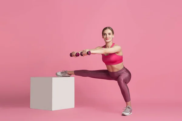 Hermosa joven atleta practicando sobre fondo de estudio rosa, retrato monocromo —  Fotos de Stock