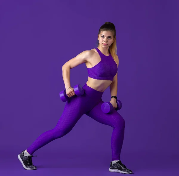 Hermosa joven atleta practicando sobre fondo púrpura estudio, retrato monocromo — Foto de Stock