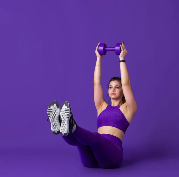 Mooie jonge vrouwelijke atleet oefenen op paarse studio achtergrond, monochrome portret — Stockfoto