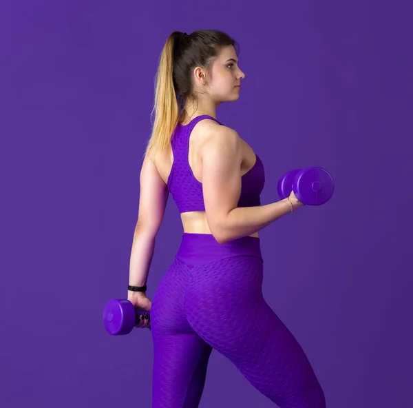 Bella giovane atleta femminile che pratica su sfondo viola studio, ritratto monocromatico — Foto Stock