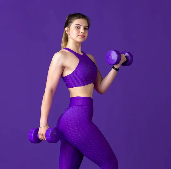 Bella giovane atleta femminile che pratica su sfondo viola studio, ritratto monocromatico — Foto Stock