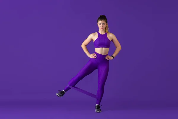 Krásná mladá žena sportovec cvičení na fialové pozadí studia, monochromatický portrét — Stock fotografie