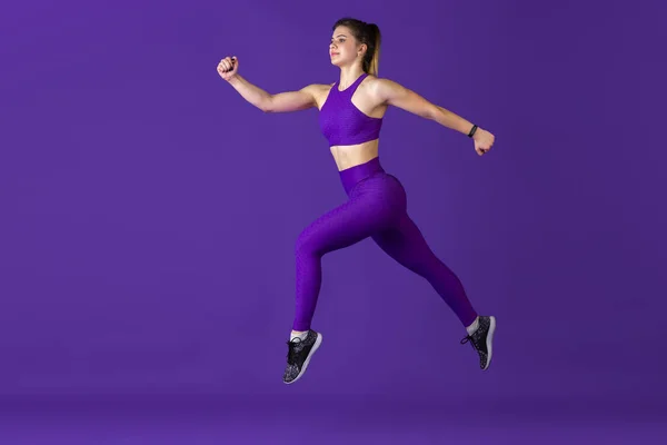 Linda jovem atleta praticando no fundo do estúdio roxo, retrato monocromático — Fotografia de Stock