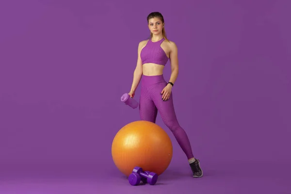 Krásná mladá žena sportovec cvičení na fialové pozadí studia, monochromatický portrét — Stock fotografie