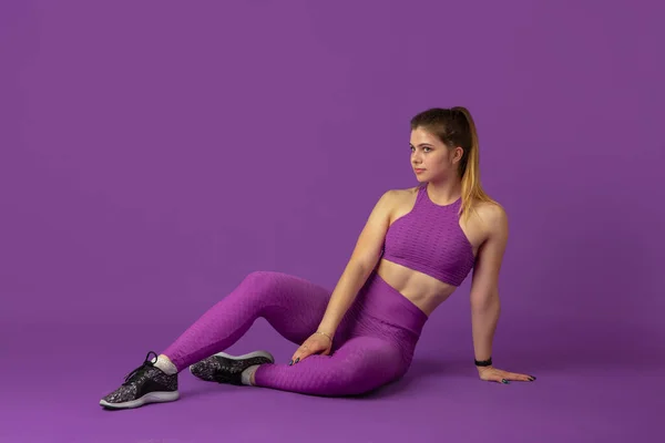 Mooie jonge vrouwelijke atleet oefenen op paarse studio achtergrond, monochrome portret — Stockfoto