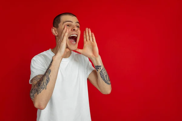 Kaukasiska unga män porträtt på röd studio bakgrund, emotinal och uttrycksfull — Stockfoto