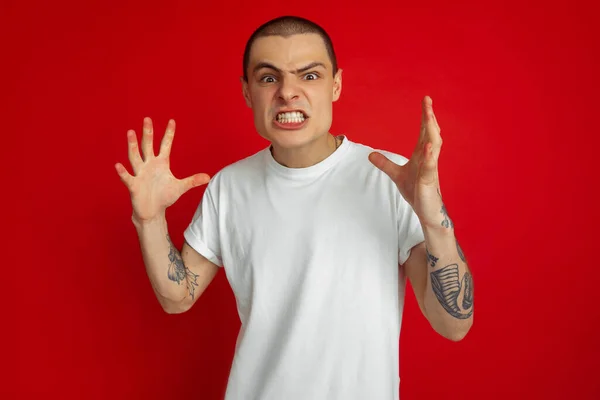 Blanc jeune homme portrait sur fond de studio rouge, émotionnel et expressif — Photo