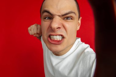 Kırmızı stüdyo arka planında beyaz erkek portresi, duygusal ve anlamlı