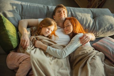 Aile evde birlikte güzel vakit geçiriyor, mutlu ve neşeli görünüyor, birlikte yatıyorlar.