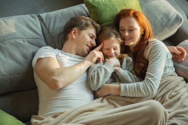 Aile evde birlikte güzel vakit geçiriyor, mutlu ve neşeli görünüyor, birlikte yatıyorlar.