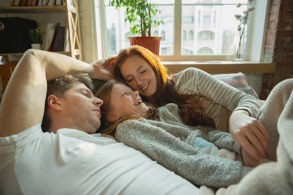 Сім'я гарно проводить час вдома, виглядає щасливою і веселою, лежить разом — стокове фото