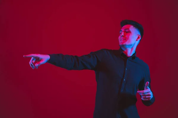 Portrait d'homme caucasien isolé sur fond de studio rouge dans la lumière bleu-violet néon, émotionnel et beau — Photo