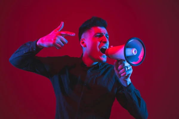 Retrato de hombre caucásico aislado sobre fondo rojo estudio en luz de neón púrpura-azul, emocional y hermoso — Foto de Stock