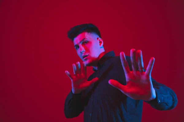 Kaukasische Männer Porträt isoliert auf rotem Studiohintergrund in lila-blauem Neonlicht, emotional und schön — Stockfoto