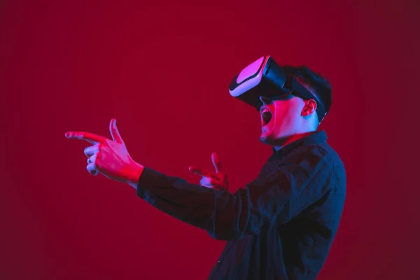 Fehér ember portré elszigetelt piros stúdió háttér lila-kék neon fény, érzelmi és gyönyörű, játék viselt VR-headset — Stock Fotó