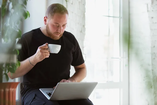 Tasarımcılar, danışmanlar, bilişim yöneticileri için çevrimiçi kurslar sırasında evde okuyan genç adam — Stok fotoğraf