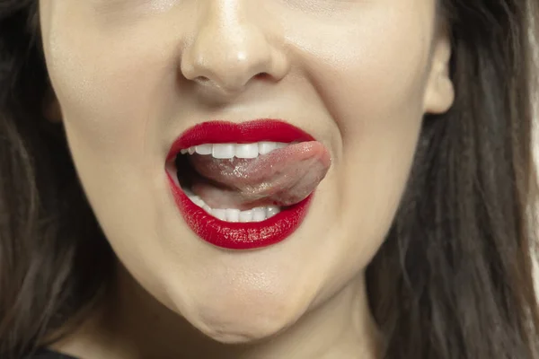 Χαμογελαστή κοπέλα που ανοίγει το στόμα της με κόκκινα χείλη και δείχνει τη μεγάλη τεράστια γλώσσα απομονωμένη σε λευκό φόντο, τρελή και ελκυστική, από κοντά — Φωτογραφία Αρχείου